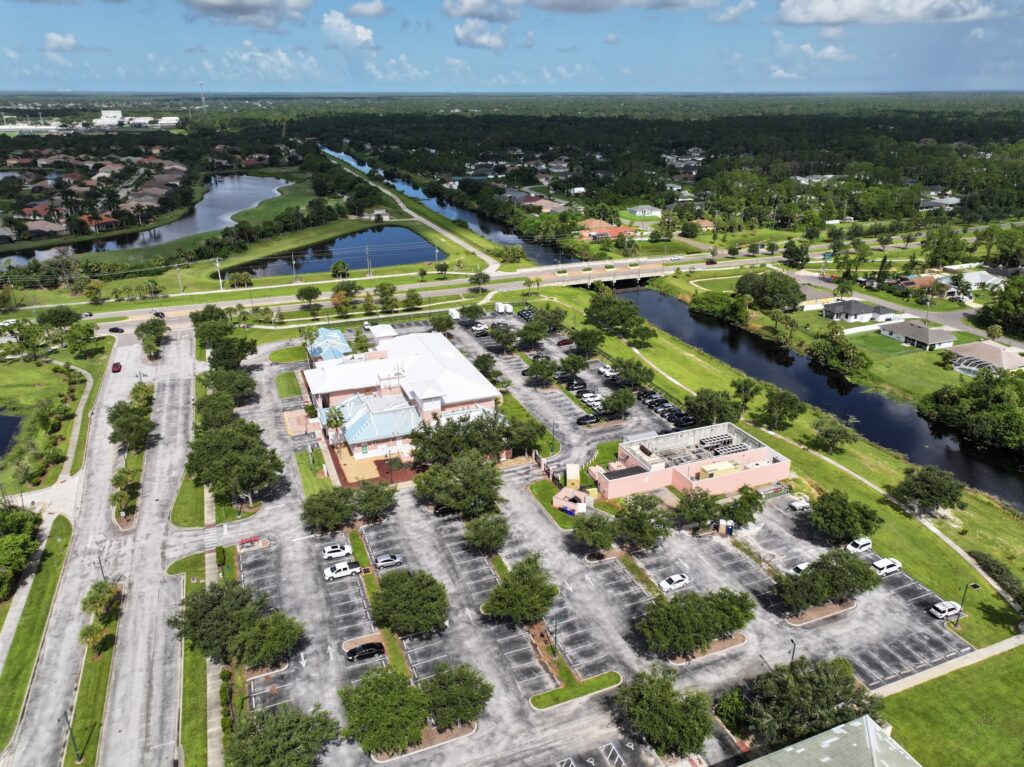 Aerial overview of a commercial development site showing buildings, roadways, and surrounding property