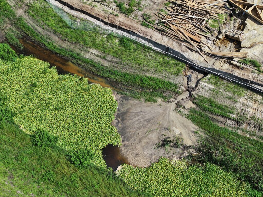 Aerial view documenting canal bank erosion, exposed soil, and adjacent vegetation