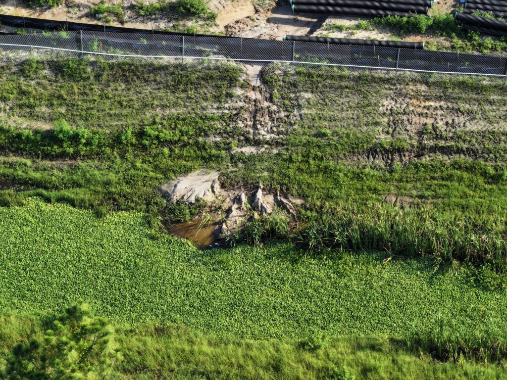 Aerial view documenting exposed soil and vegetation along a canal bank