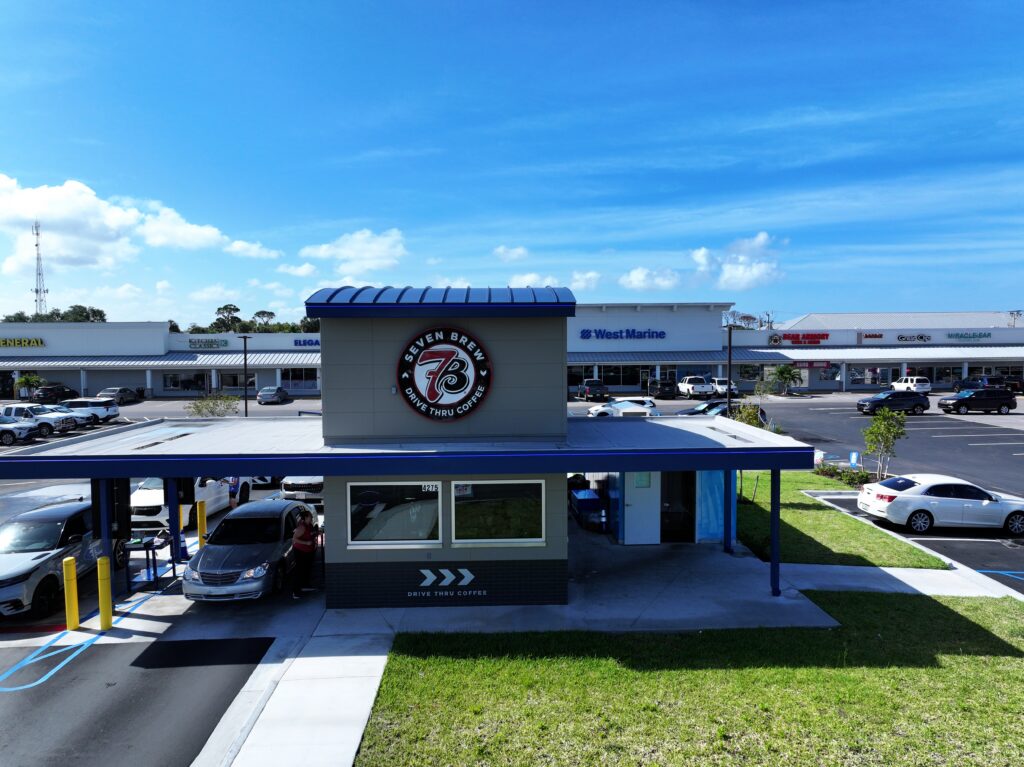 Aerial view of a drive-thru coffee shop and surrounding commercial shopping center