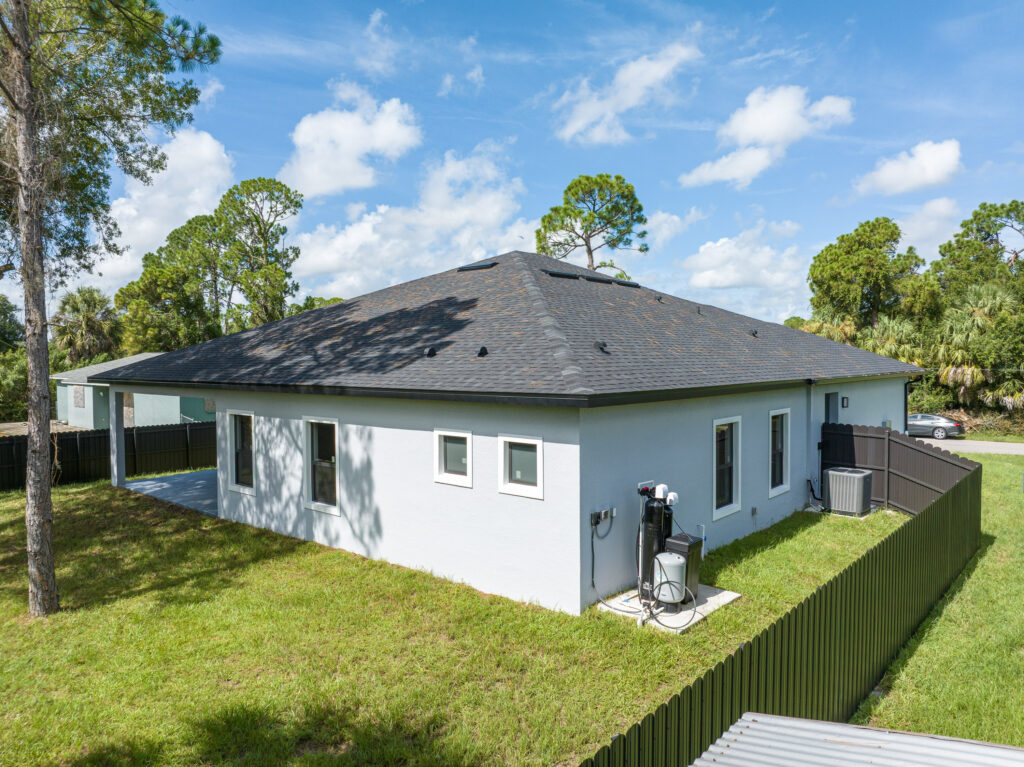 Elevated aerial view of a single-story home, yard, and surrounding property