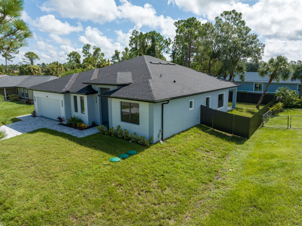 Elevated aerial view of the front exterior, fenced yard, and lawn of a single-story home