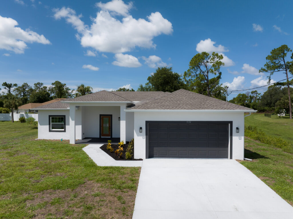 Front aerial view of a modern residential home with two-car garage and driveway