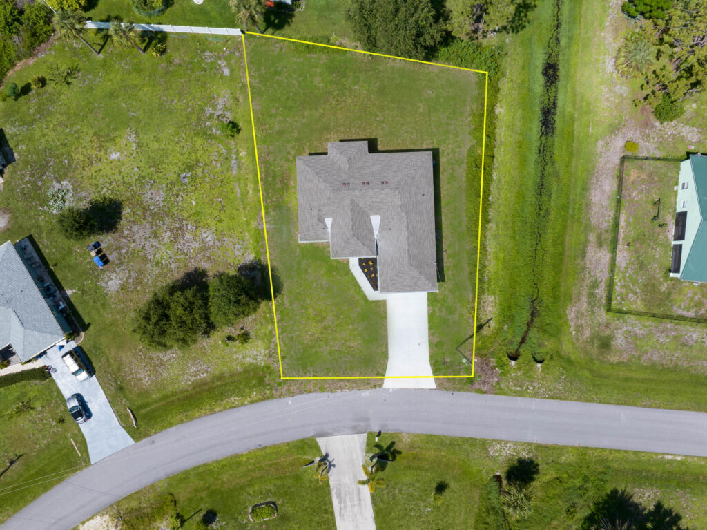 Overhead aerial view of a single-story home, driveway, lawn, and visible property boundaries