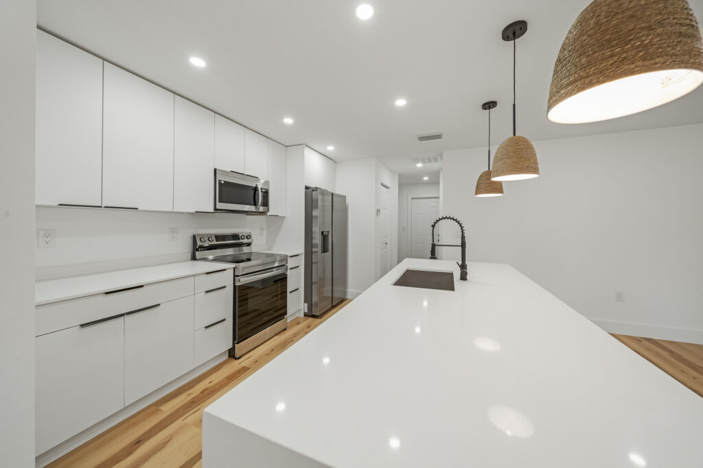 Modern kitchen with white cabinetry, quartz countertops, stainless-steel appliances, and a large island