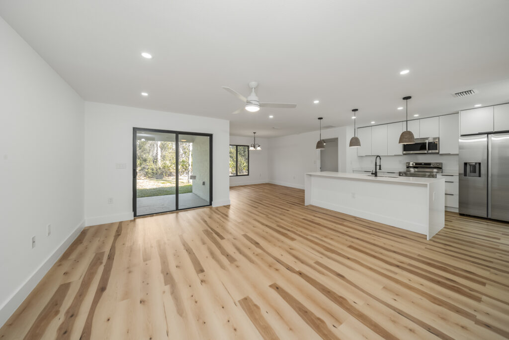 Bright open-concept living area and kitchen with wood-look flooring, recessed lighting, and large windows