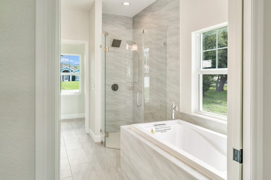 Bright primary bathroom with a soaking tub, walk-in shower, tiled walls, and large window